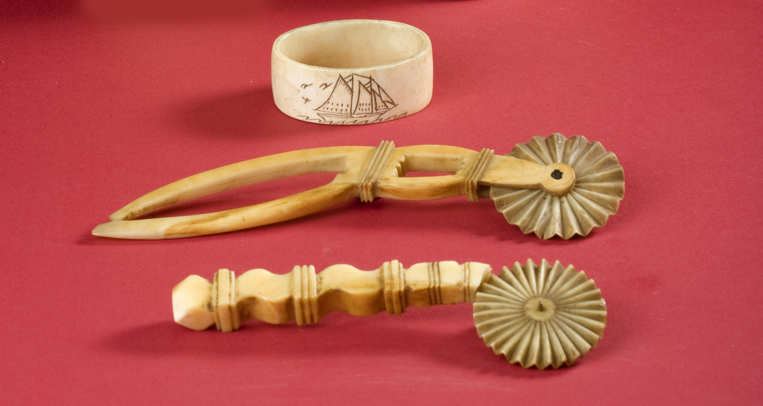 TWO SCRIMSHAW PIE CRIMPERS Together with a walrus tusk napkin