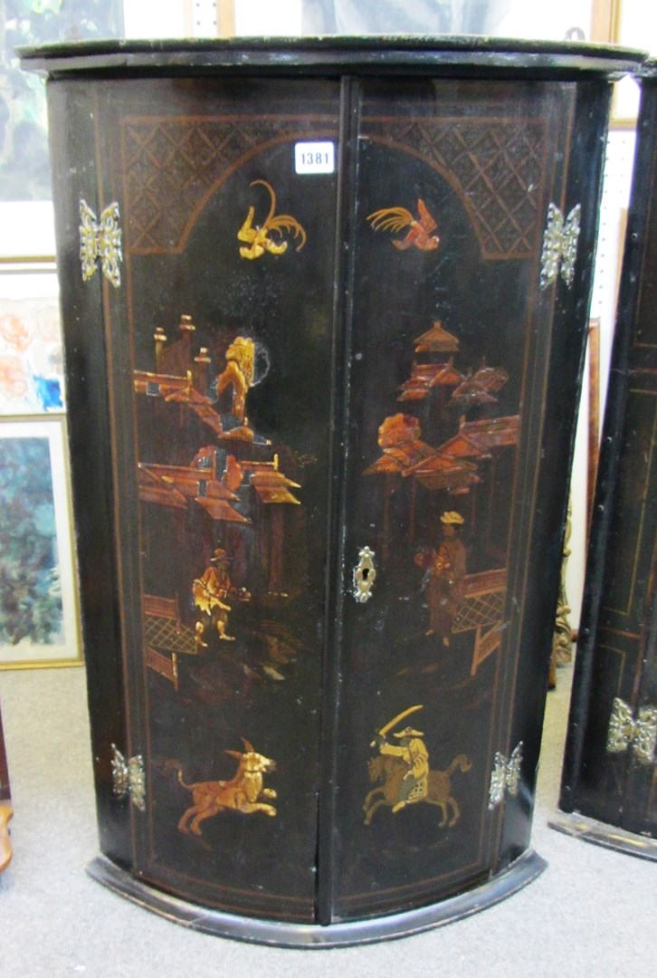 An 18th century black lacquer chinoiserie decorated bowfront hanging two