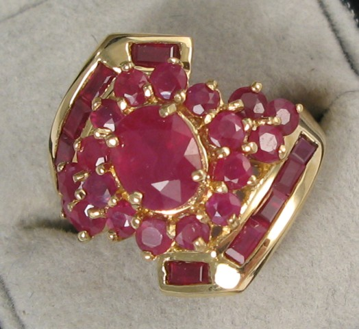 RUBY AND FOURTEEN KARAT GOLD RING centering an oval cut