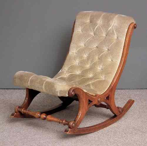 A Victorian walnut framed rocking nursing chair of scrolled shape