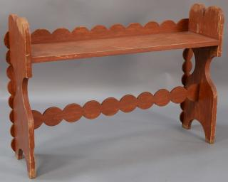 Red painted bucket bench having scallop carved back and support