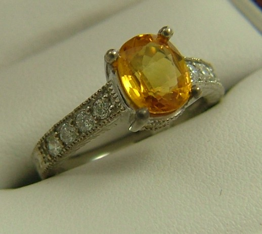 ORANGE SAPPHIRE DIAMOND AND FOURTEEN KARAT GOLD RING centering an
