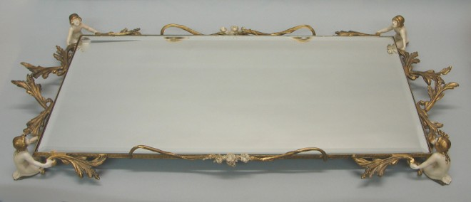 Vanity tray features three dimensional putti figures on border mirror