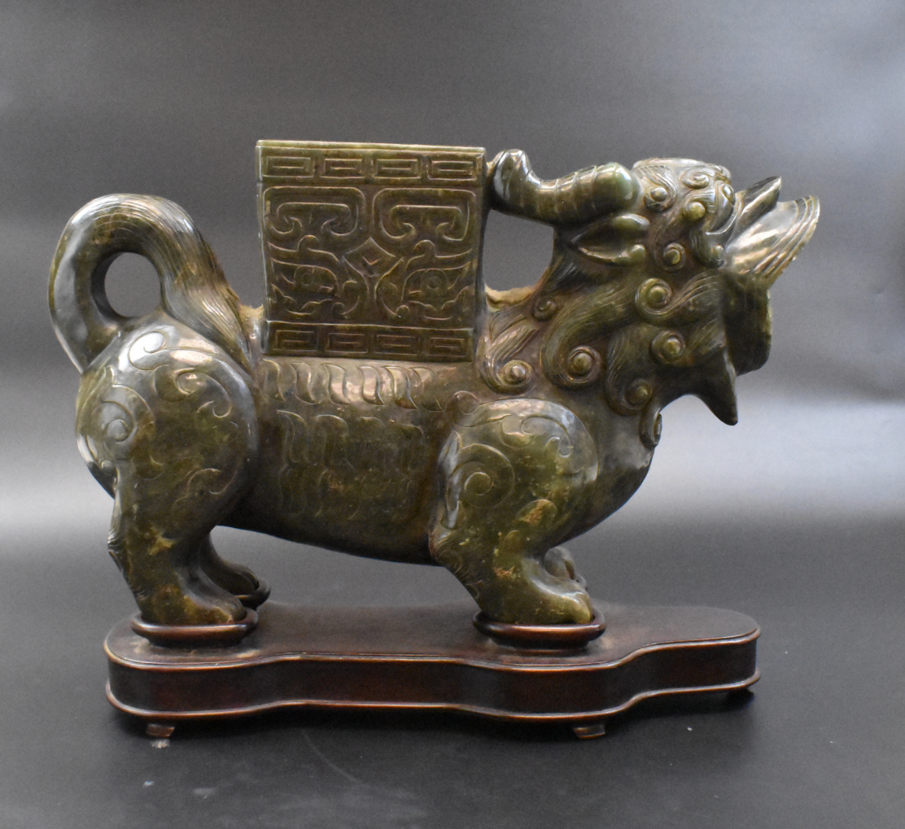 A Chinese spinach jade Foo Lion vase with wood base