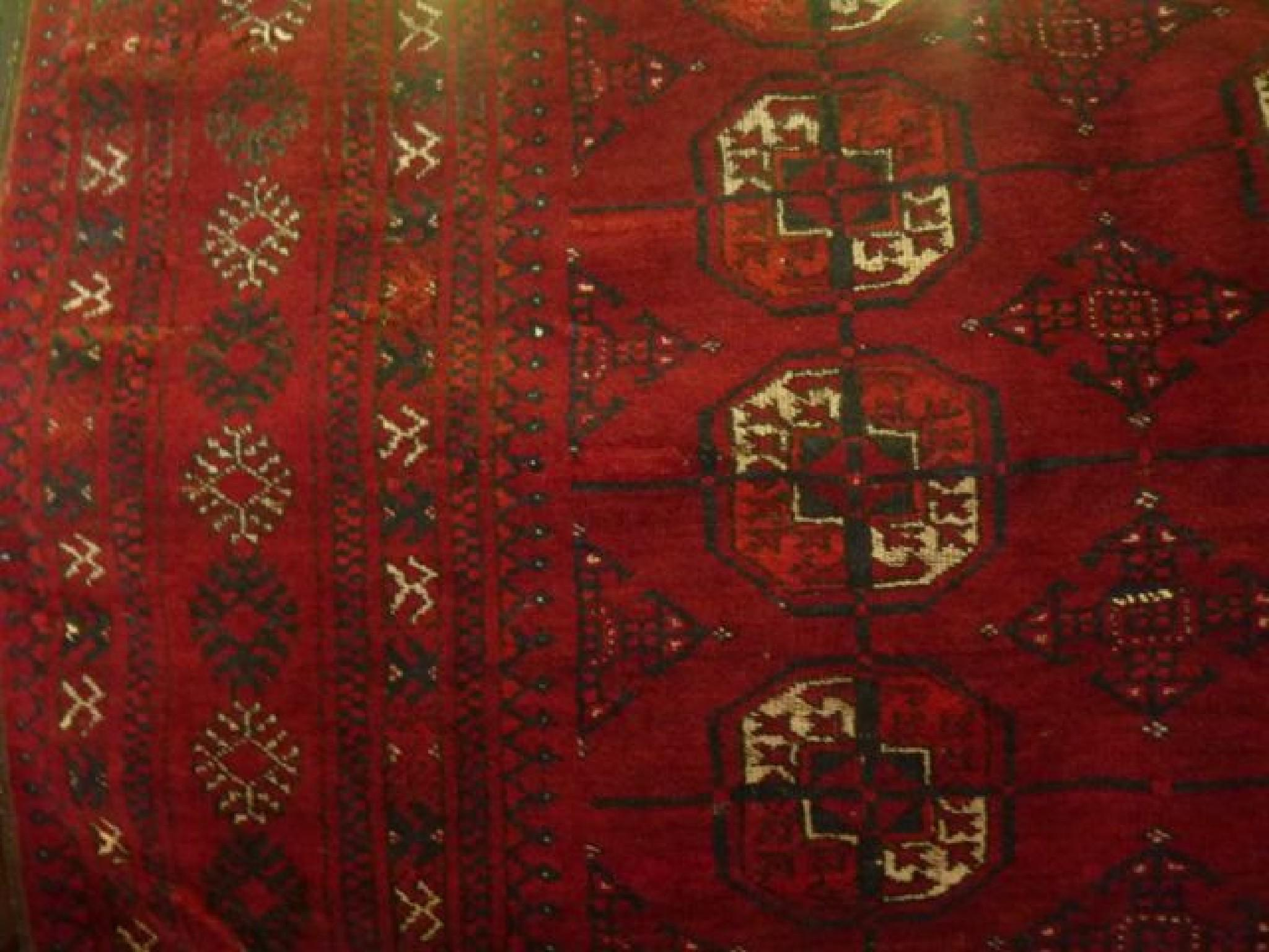 An Afghan red ground wool carpet with multi medallion detail