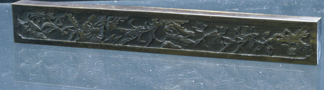 A scroll rest with carved decoration of various insects midst
