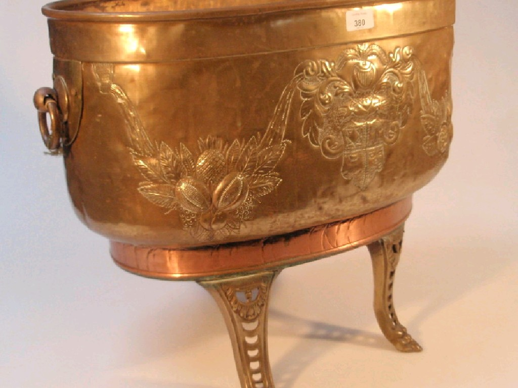 A brass and copper oval planter with ring handles and