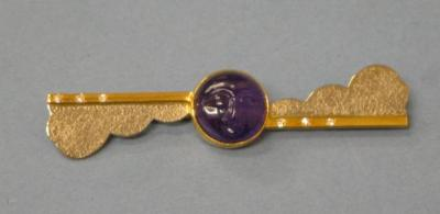 AN AMETHYST BROOCH the circular cabochon amethyst carved with a