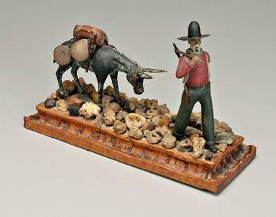 Carved prospector mule walking through rocky area mule staring at