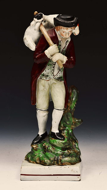 Prattware model of a shepherd carrying a lambon a square