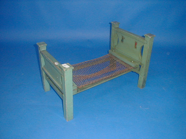 A green painted dolls bed with wire base