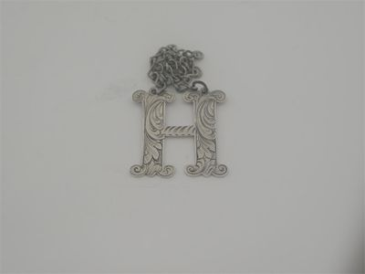 A cut out letter H wine label incised with scrolling