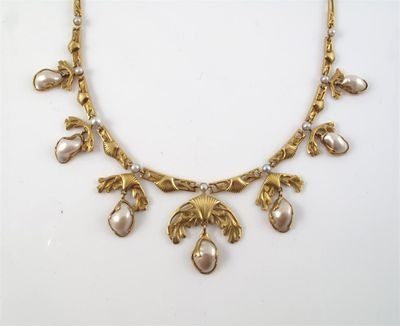 A gold necklace with graduated foliate pendant mounted with baroque