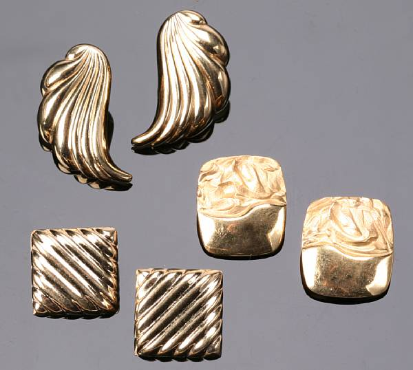 A collection of gold ear clips and a lapel pin