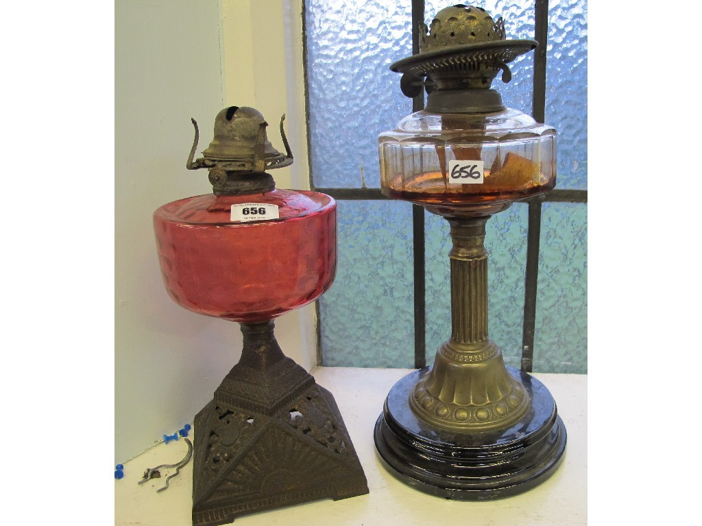 Two parafin lamps one with cranberry gass reservoir