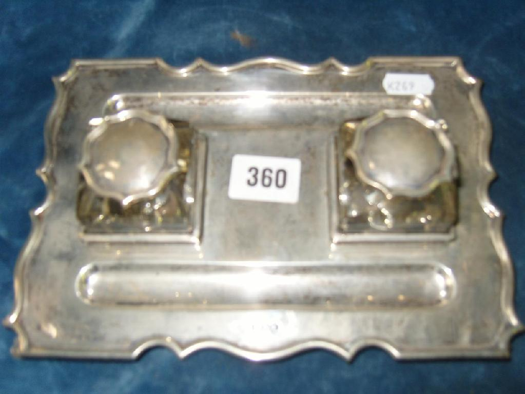 A silver inkstand of shaped form and stylised supports fitted