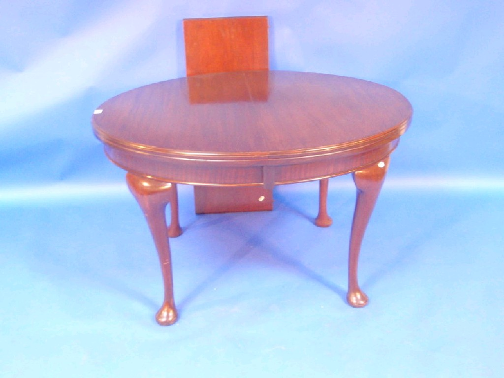 A George V mahogany extending dining table with oval moulded