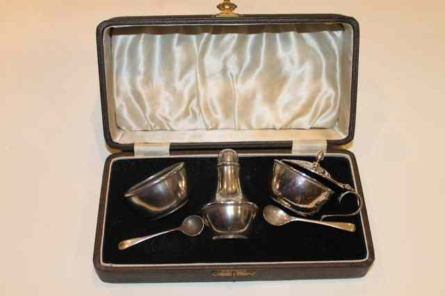 A SILVER THREE PIECE CONDIMENT CASE comprising a pepper pot