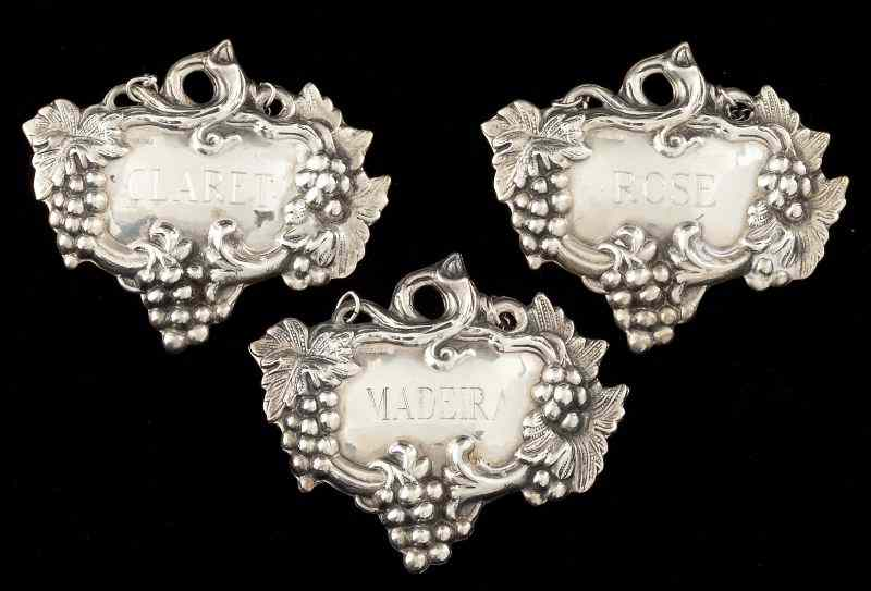 Three Sterling Decanter Labelseach with grape motif engraved Claret Rose