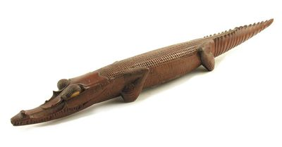 A carved wood model of a crocodile with cowrie shell