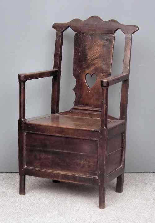 An 18th Century panelled oak commode armchair with shaped cresting