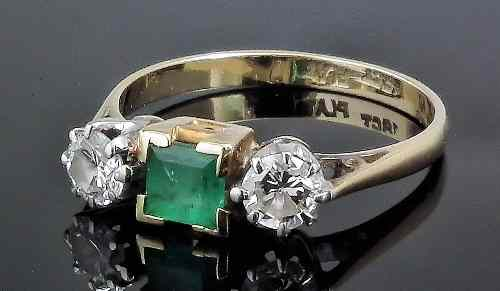 A modern 18ct gold and platinum mounted three stone emerald