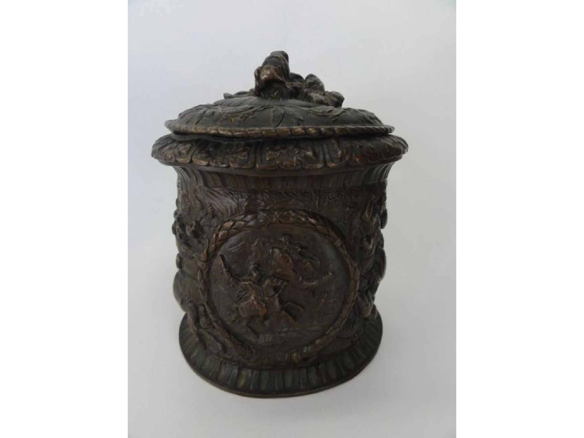 A cast metal vessel of cylindrical form with deep embossed
