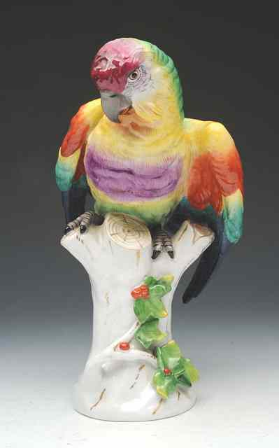 AN EARLY 20TH CENTURY CONTINENTAL PORCELAIN PARROT perched on a