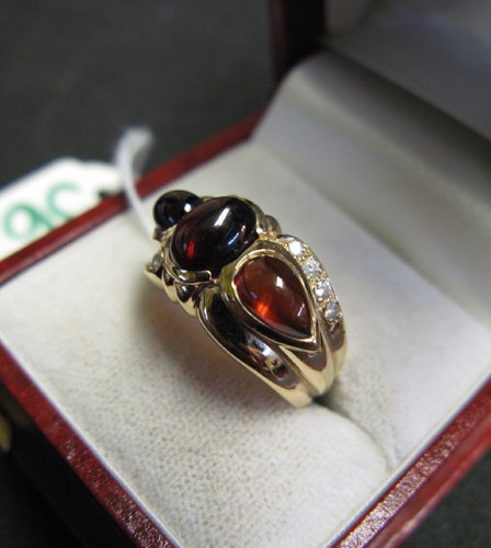 GARNET DIAMOND AND FOURTEEN KARAT GOLD RING centering an oval
