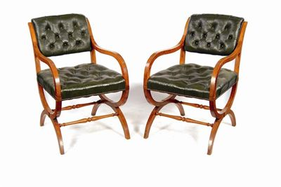 A pair of oak X frame open armchairs upholstered buttoned