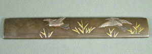A Japanese bronze Kozuka decorated with flying cranes signed length