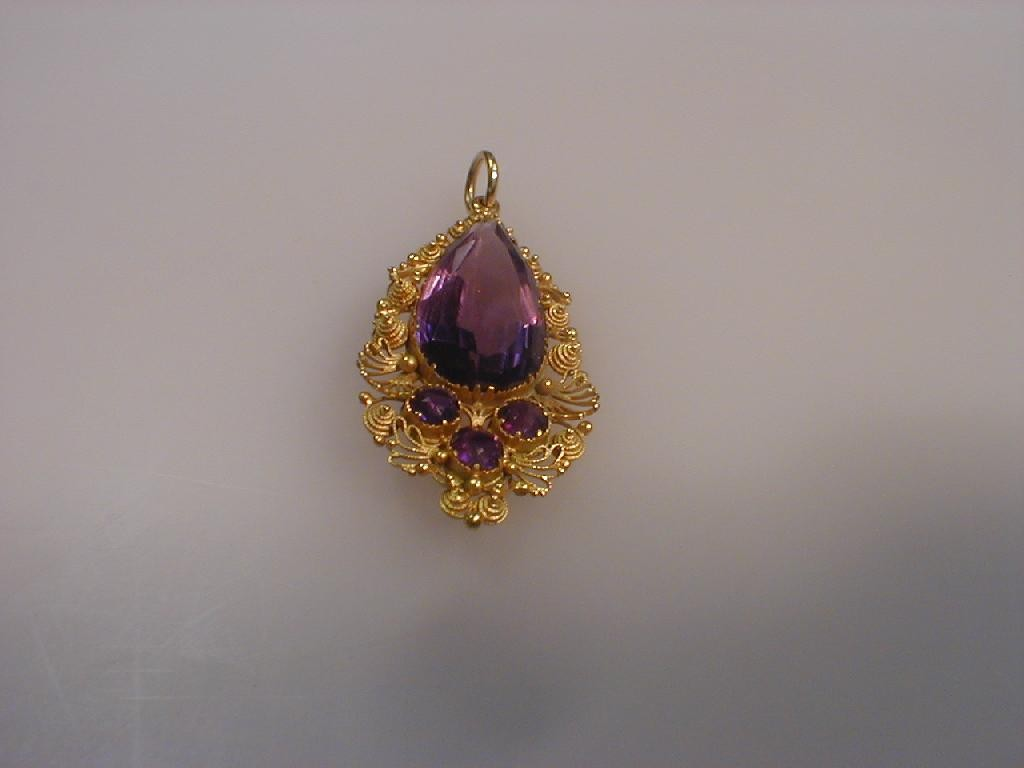 A tear drop shaped amethyst set pendant filigree yellow metal