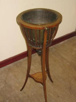AN EDWARDIAN MAHOGANY JARDINIERE STAND of circular slatted form crossbanded