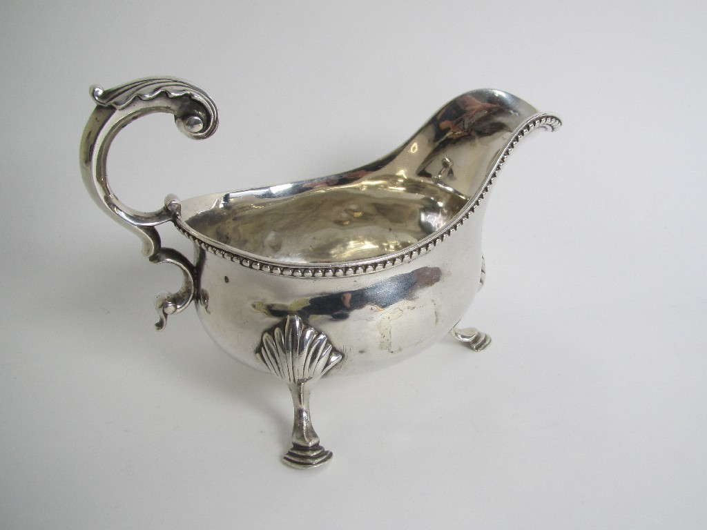 A silver sauceboat with gadroon rim double C scroll handle