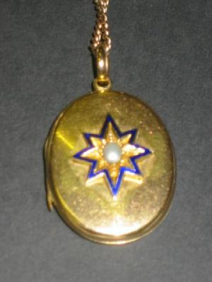 A VICTORIAN GOLD LOCKET of hinged oval form the front