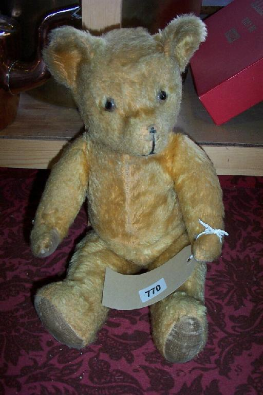 A golden plush teddy with velvet pads and glass eyes