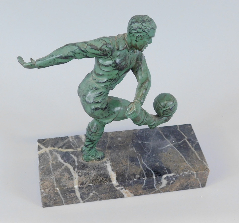 A bronzed spelter model of a footballer kicking a ball