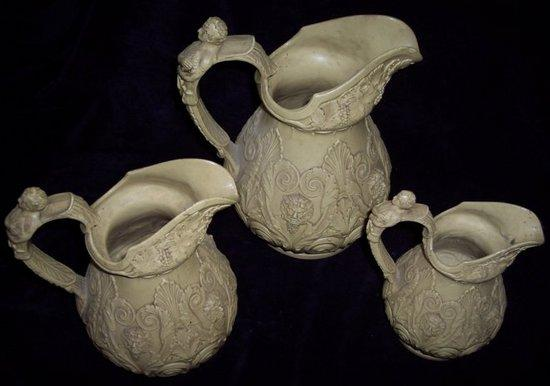 A graduated set of three pottery jugs decorated in relief