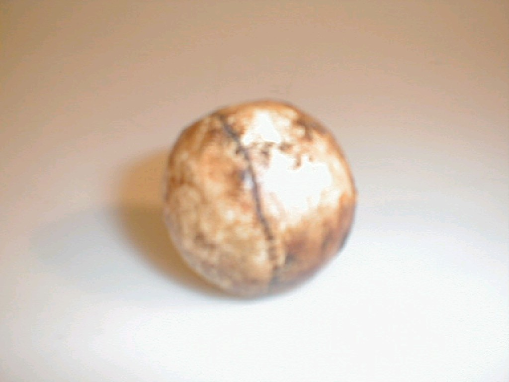 A reproduction feather golf ball with faux stitch marks and