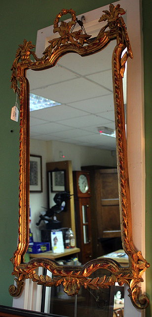 A CARVED GILT WOOD HANGING WALL MIRROR with shaped mirror