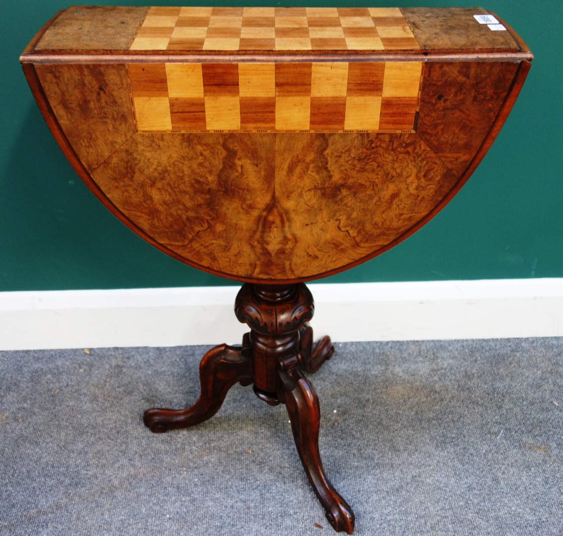 A Victorian figured walnut drop flap games table on carved