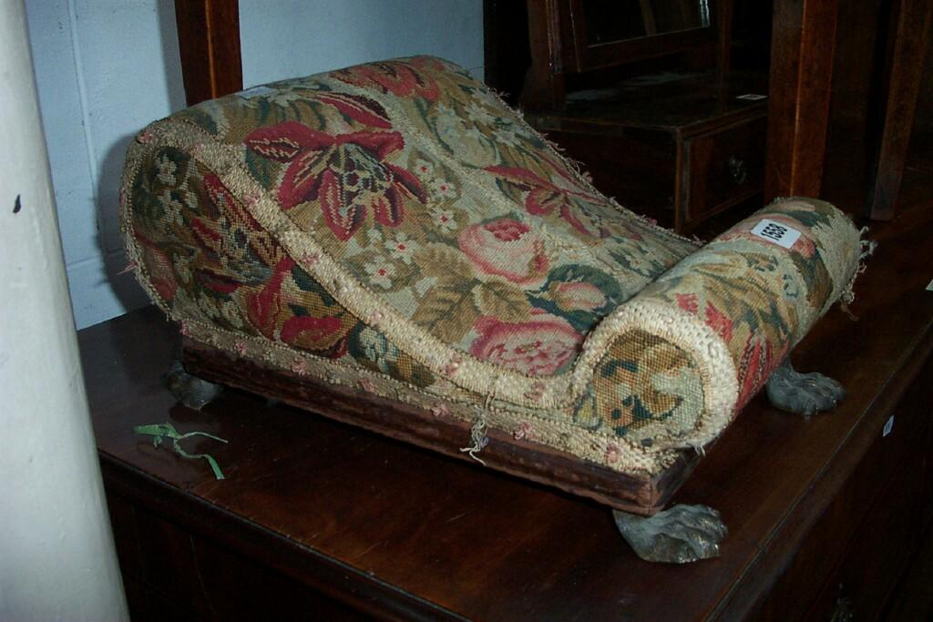 An early 19th century footstool of scrolled outline with brass