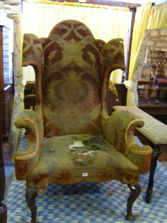 An Edwardian Georgian style wing armchair of extravagant form with