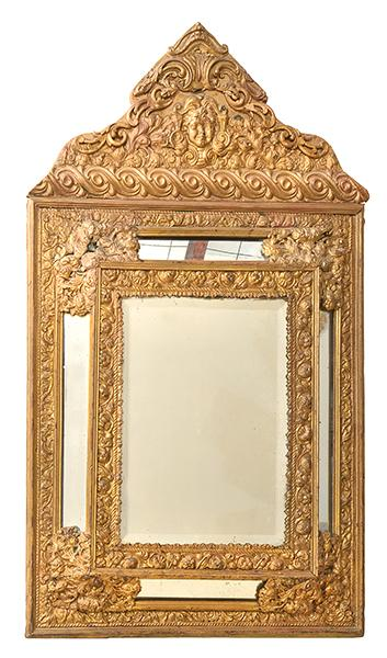 AN EMBOSSED BRASS MOUNTED CUSHION FRONT WALL MIRROR with a