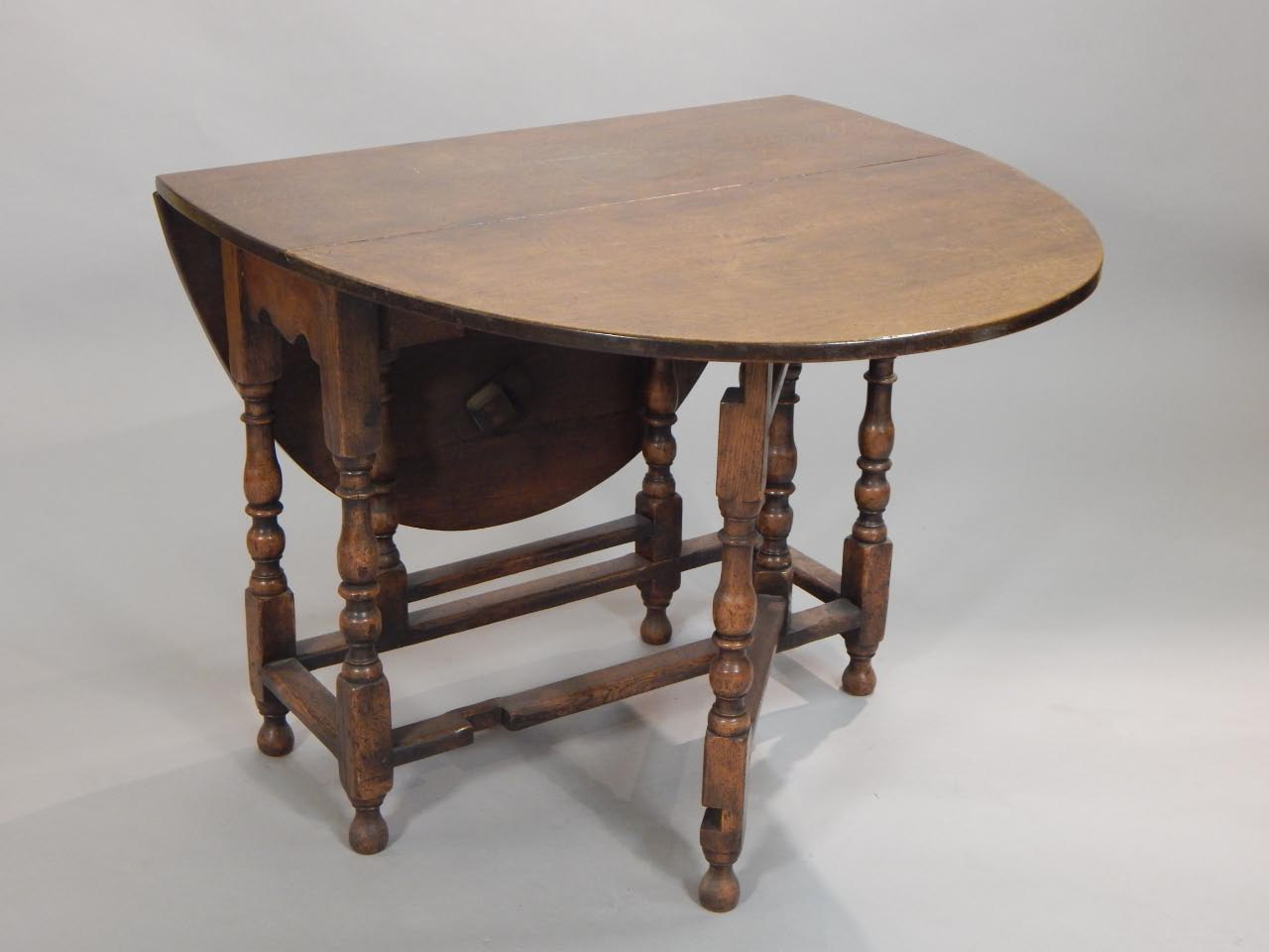 An oak gate leg table the oval top on turned