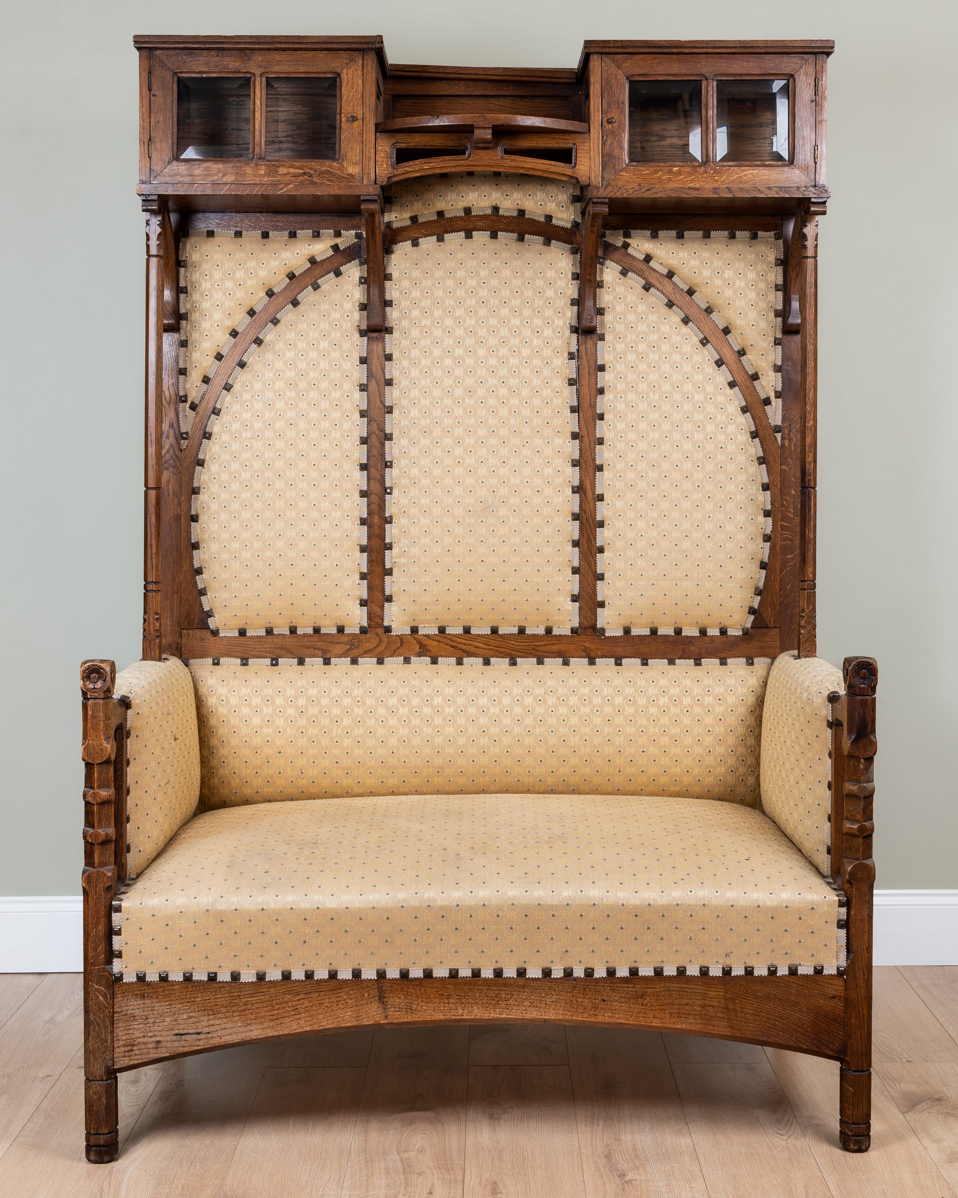 A Victorian oak Arts Crafts settle with glazed cupboards either