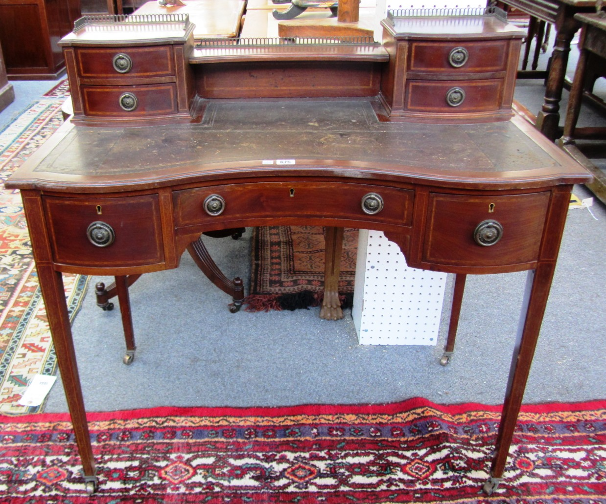 An Edwardian inlaid mahogany concave fronted writing table with seven