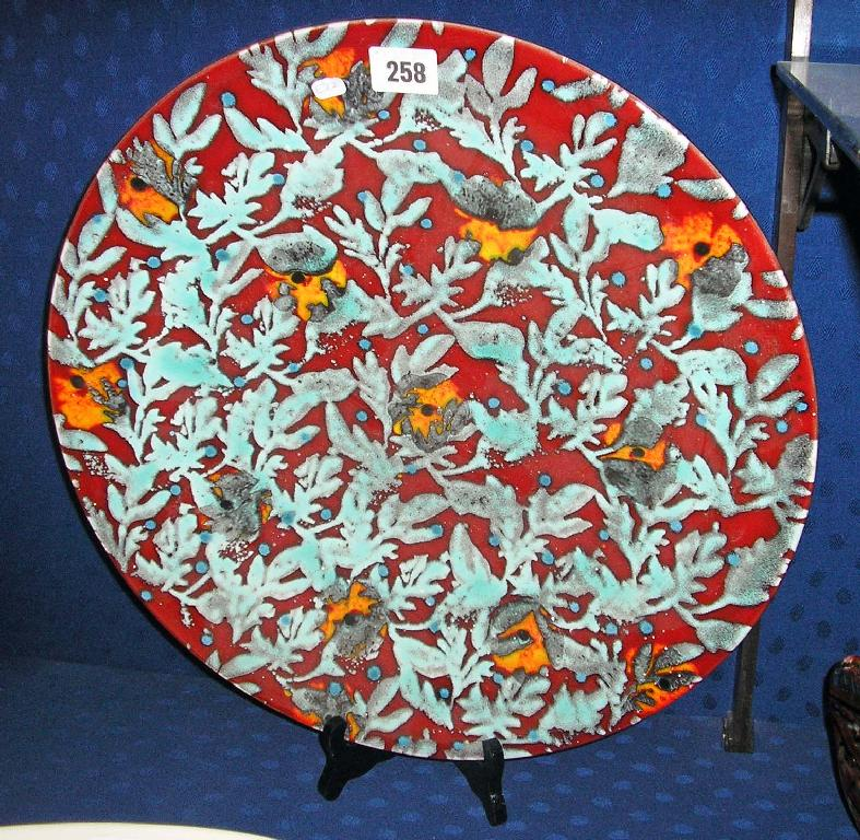 A Poole pottery charger decorated with green foliage against a