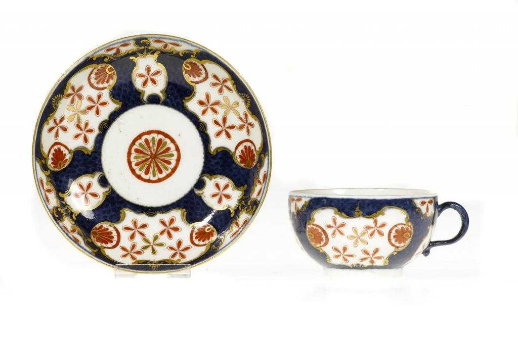 A WORCESTER SCALE BLUE GROUND TEACUP AND SAUCER enamelled in