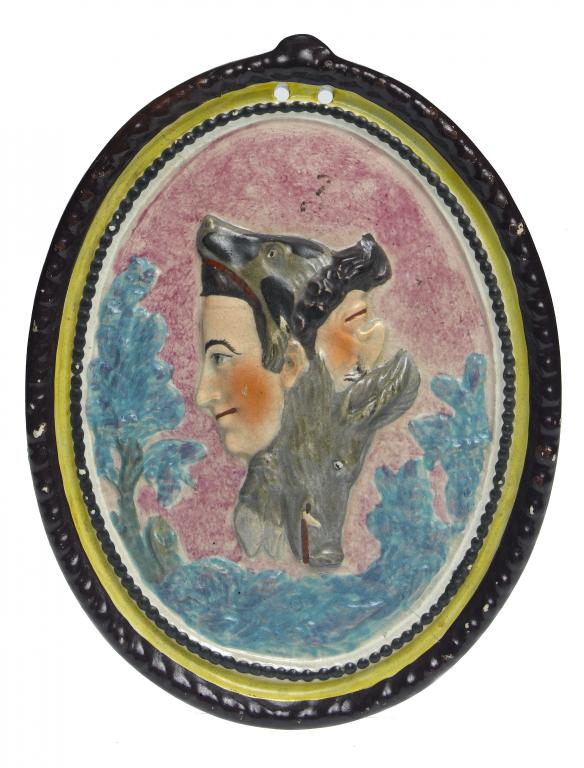 A PEARLWARE OVAL PLAQUE moulded in relief with transforming masks